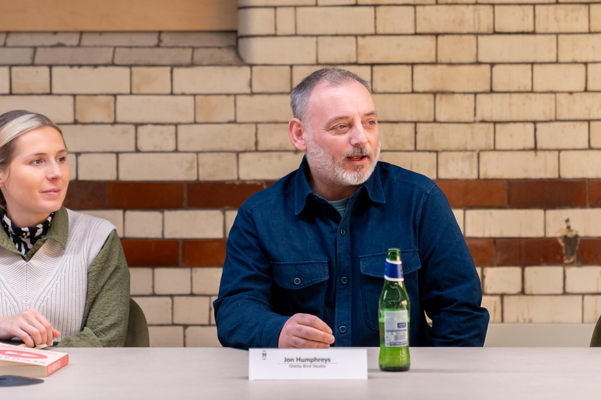 Discussion on EDI culture featuring Jon Humphreys at Material Source Studio, with beer bottle and a collaborative atmosphere.