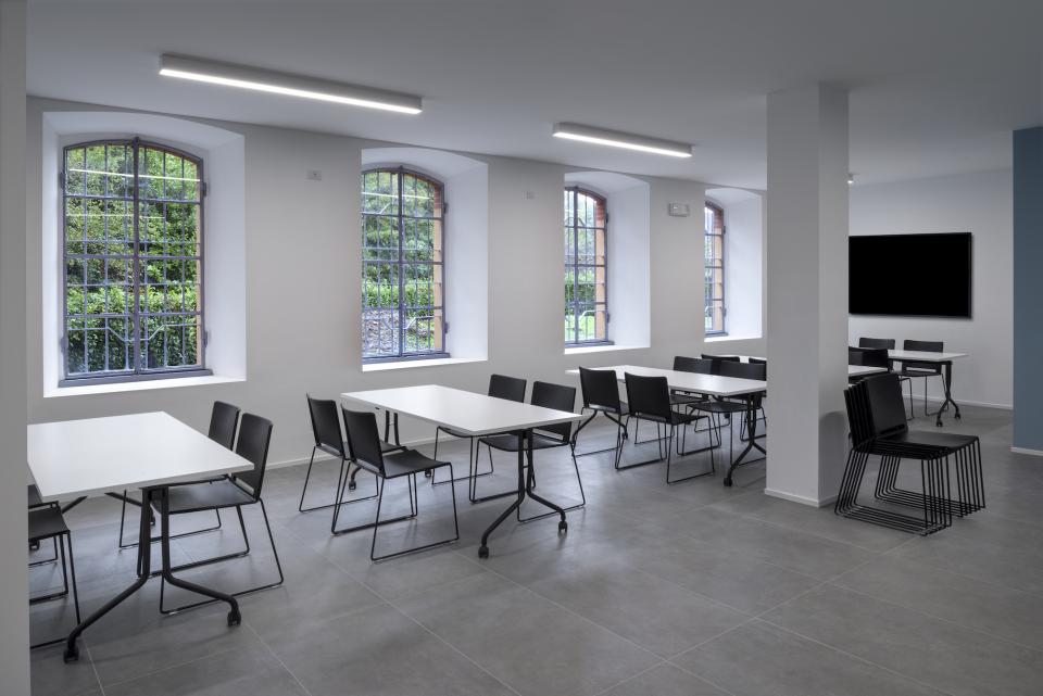 Modern office space with tables and chairs, featuring large windows, showcasing the new T&T headquarters' design.