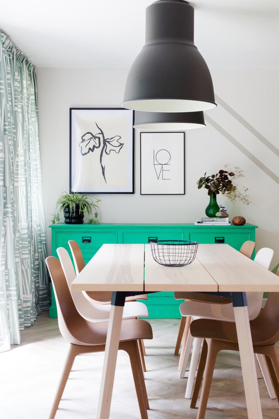 Bright dining area featuring a wooden table, stylish chairs, and vibrant green cabinetry in Scandi Industrial design.
