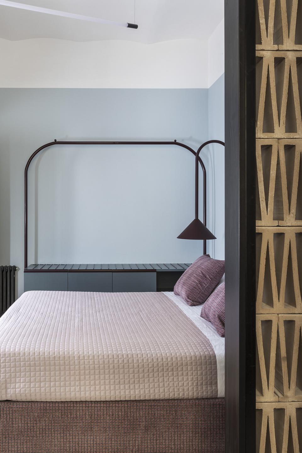Stylishly designed bedroom with a modern bed, unique shelving, and soft color tones in a compact Trastevere apartment.