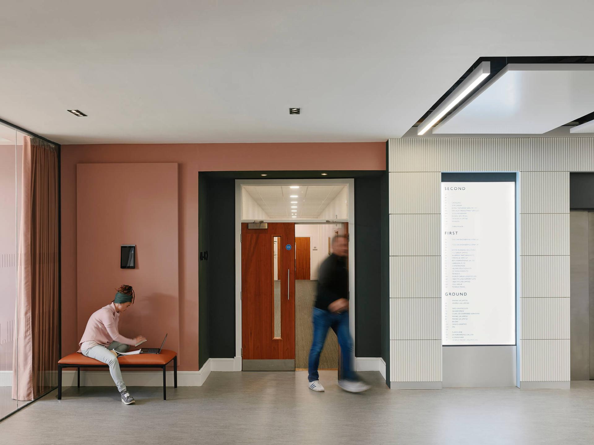 Welcoming interior of Manchester International Office Centre featuring vibrant colors, a seating area, and directional signage.