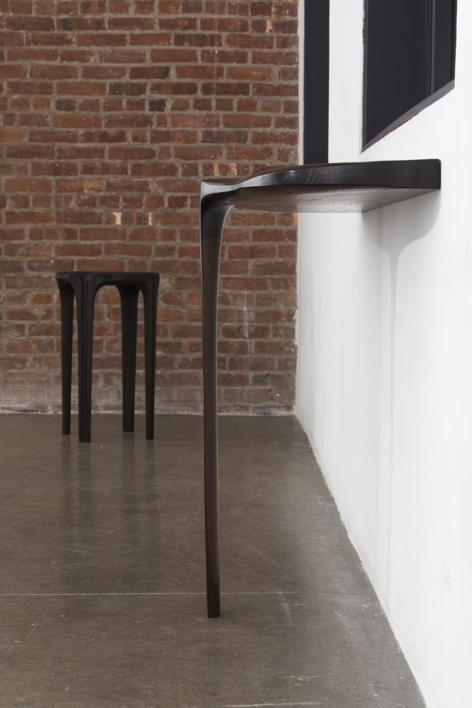 Sleek, modern furniture pieces inspired by the 18th-century Birdcage Windsor chair against a brick wall backdrop.