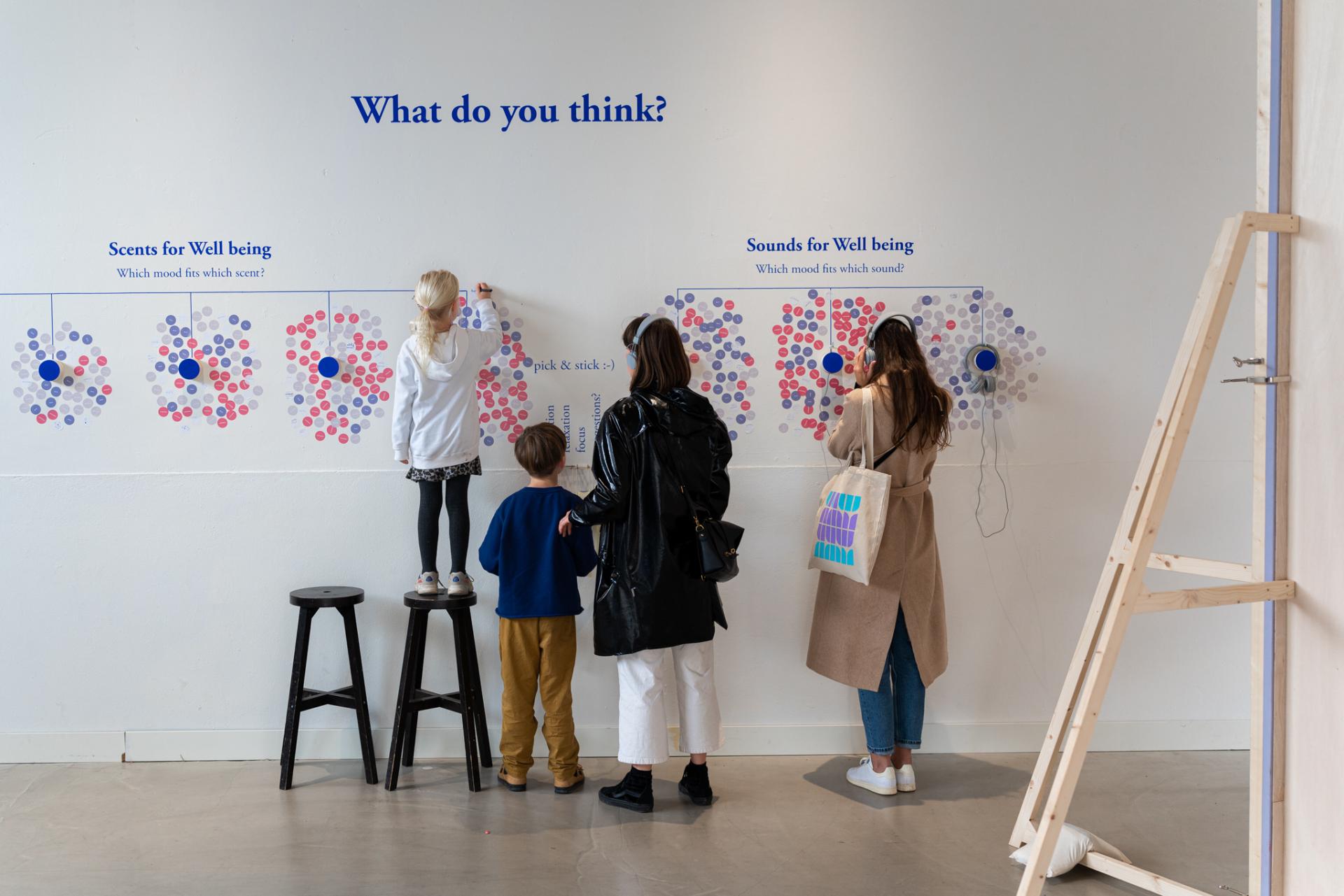 Visitors interact with a sensory wall exploring connections between scents and sounds for wellbeing design.