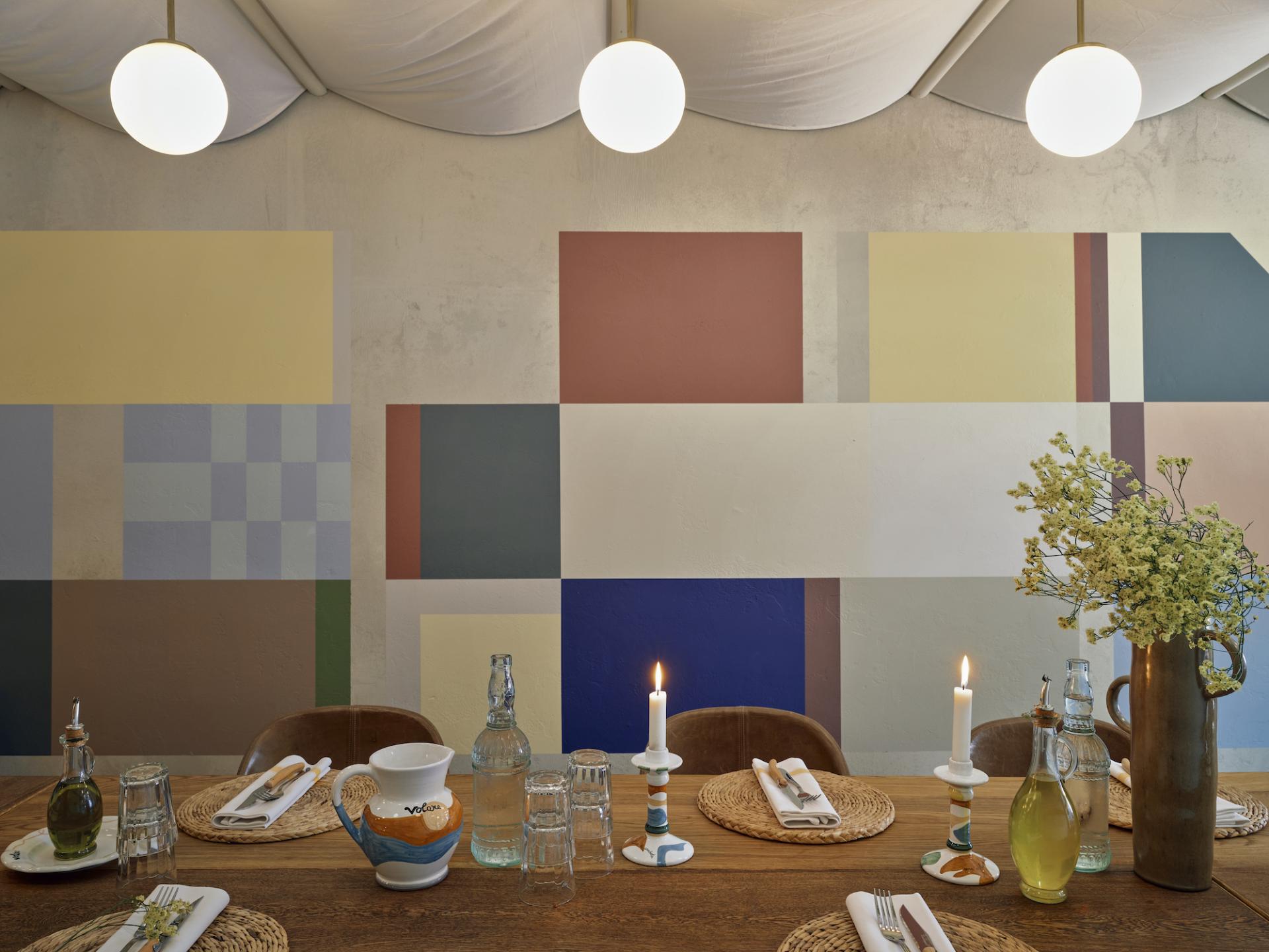 Rustic Italian dining table at Volare, adorned with candles, rustic decor, and vibrant wall art reminiscent of the Amalfi Coast.