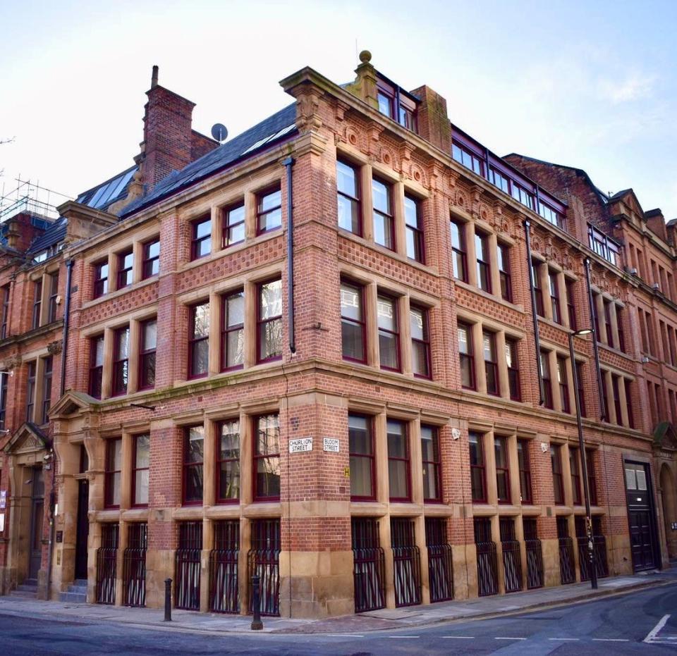 Victorian warehouse exterior transformed into luxury apartments, showcasing red brick architecture and large windows.