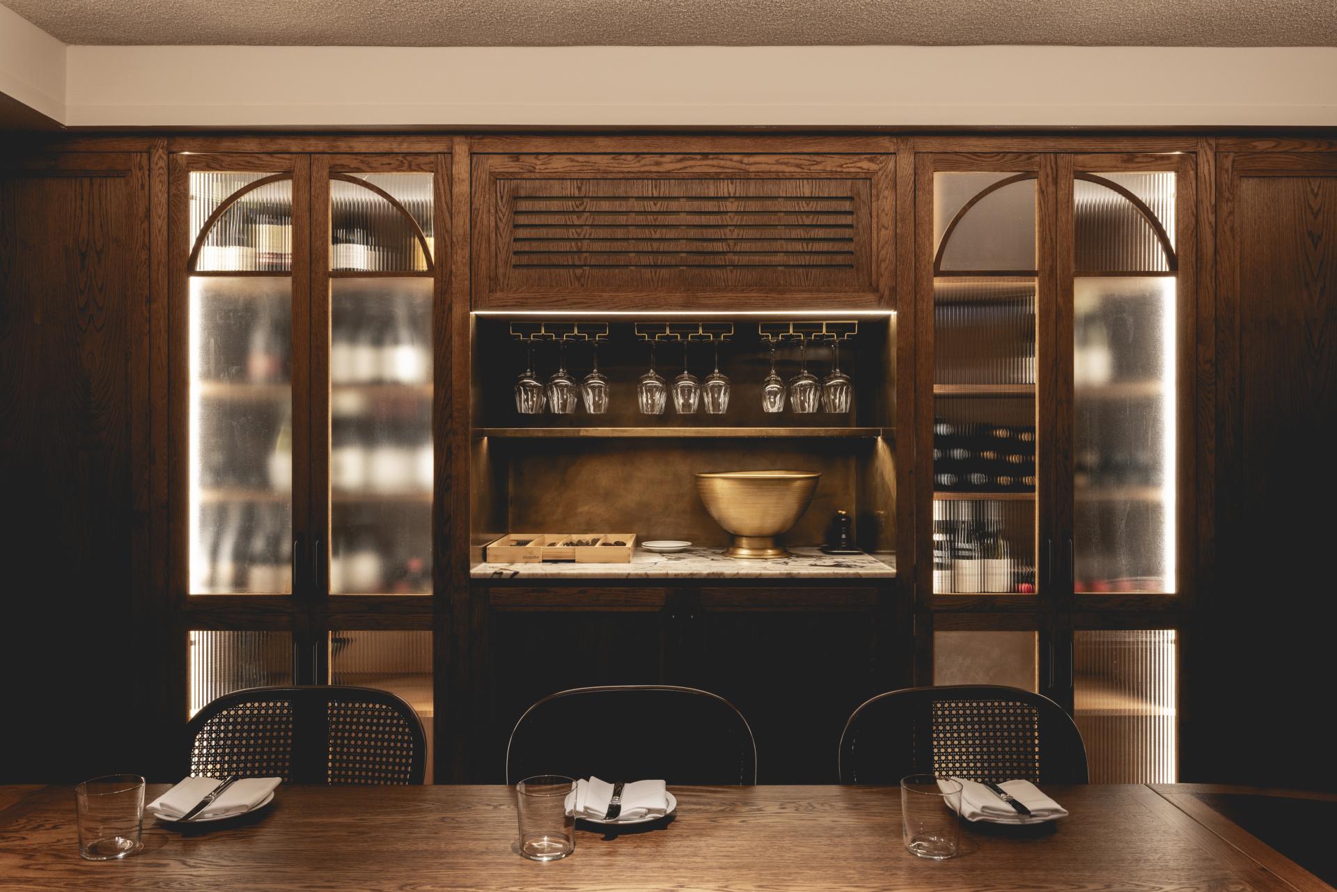 Elegant dining area featuring rustic wooden cabinetry, glassware, and stylish table settings at Fitzrovia restaurant.