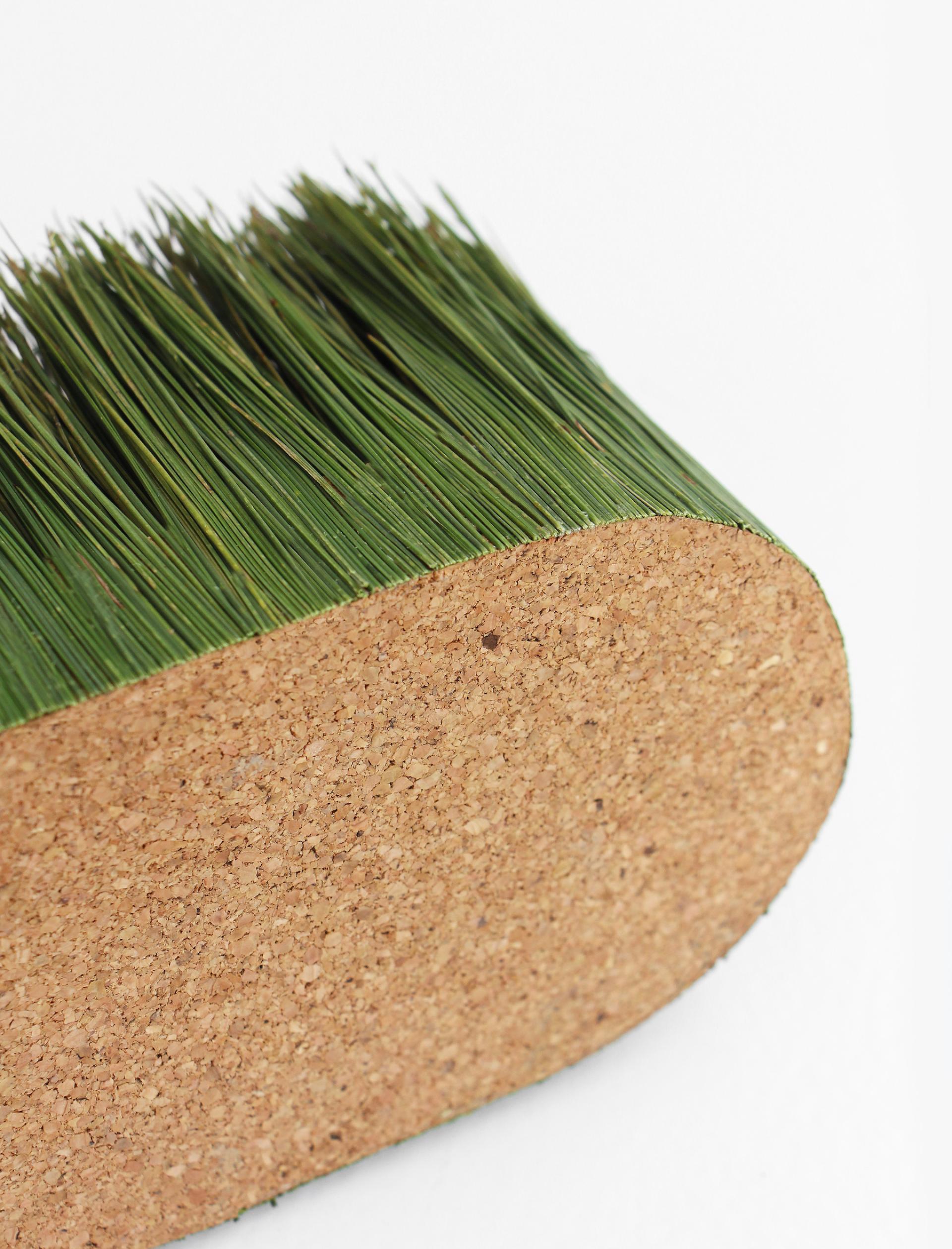 Green artificial grass with a textured cork base, symbolizing creativity in vessel design and construction.