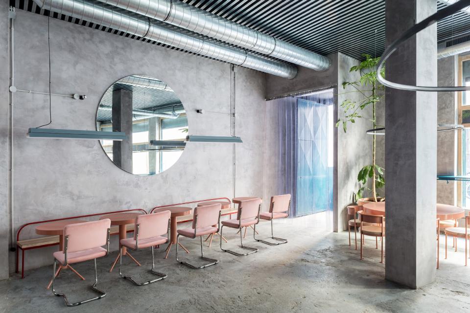 Contemporary restaurant interior featuring concrete walls and pastel-colored furniture, highlighting modern design elements in Seville.