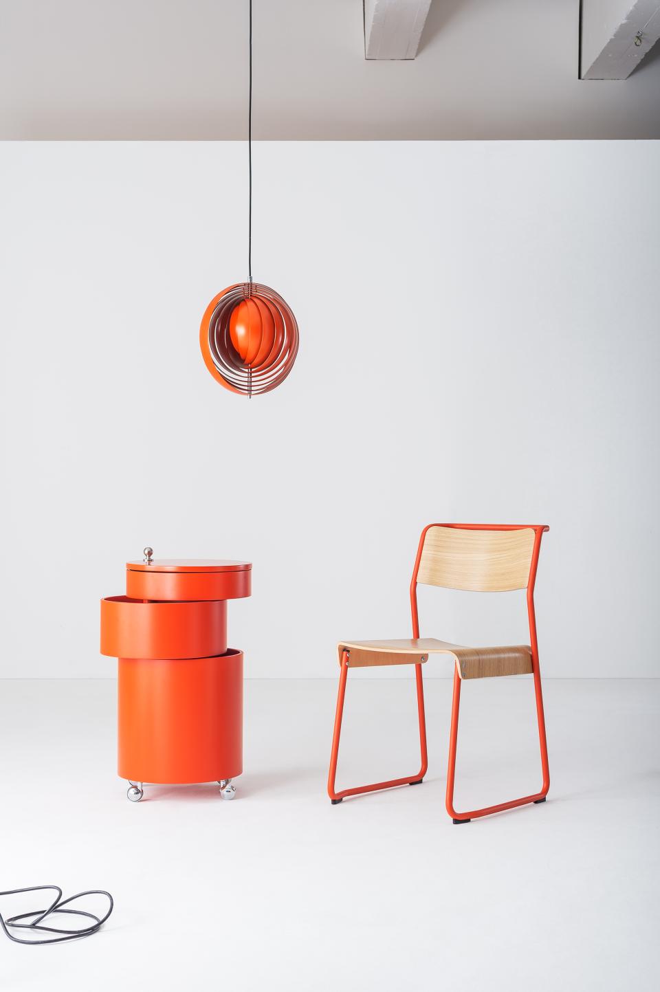 Vibrant red furniture including a modern light fixture and stylish chair, reflecting designjunction's (Re)act theme for this year's show.
