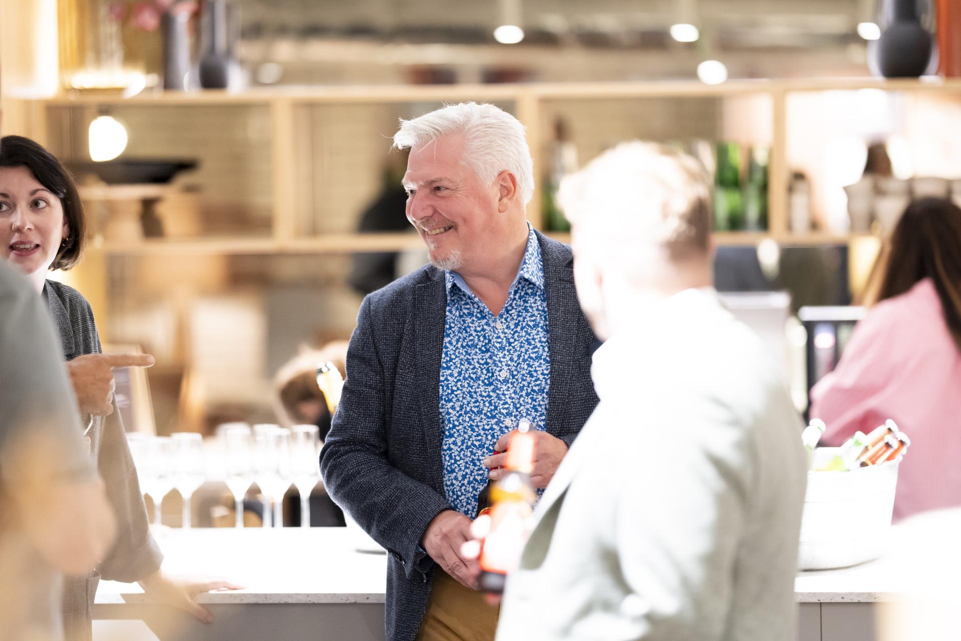 Networking event in a modern workspace, featuring professionals discussing technology's role in workplace dynamics.