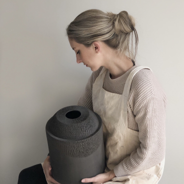 Sophie Farrar, a Sheffield ceramic artist, holds a textured black ceramic piece, showcasing her hand-building technique.