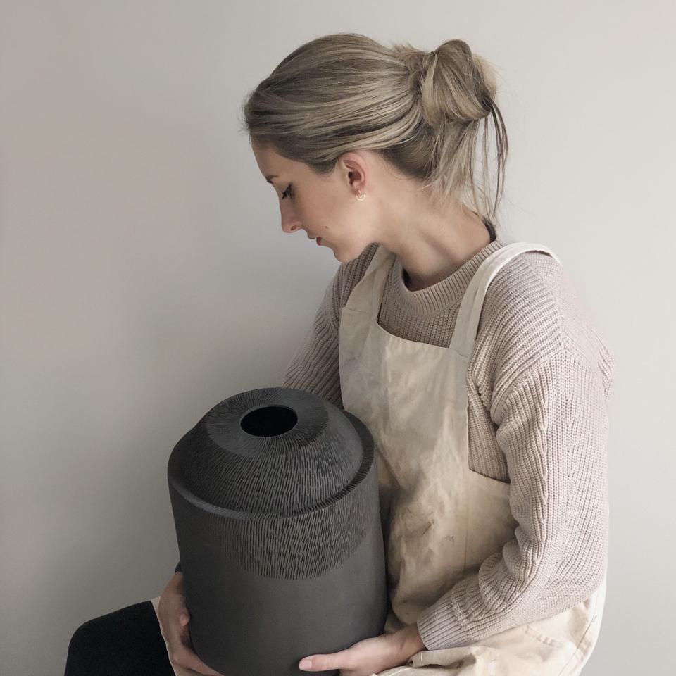 Sophie Farrar, a Sheffield ceramic artist, holds a textured black ceramic piece, showcasing her hand-building technique.