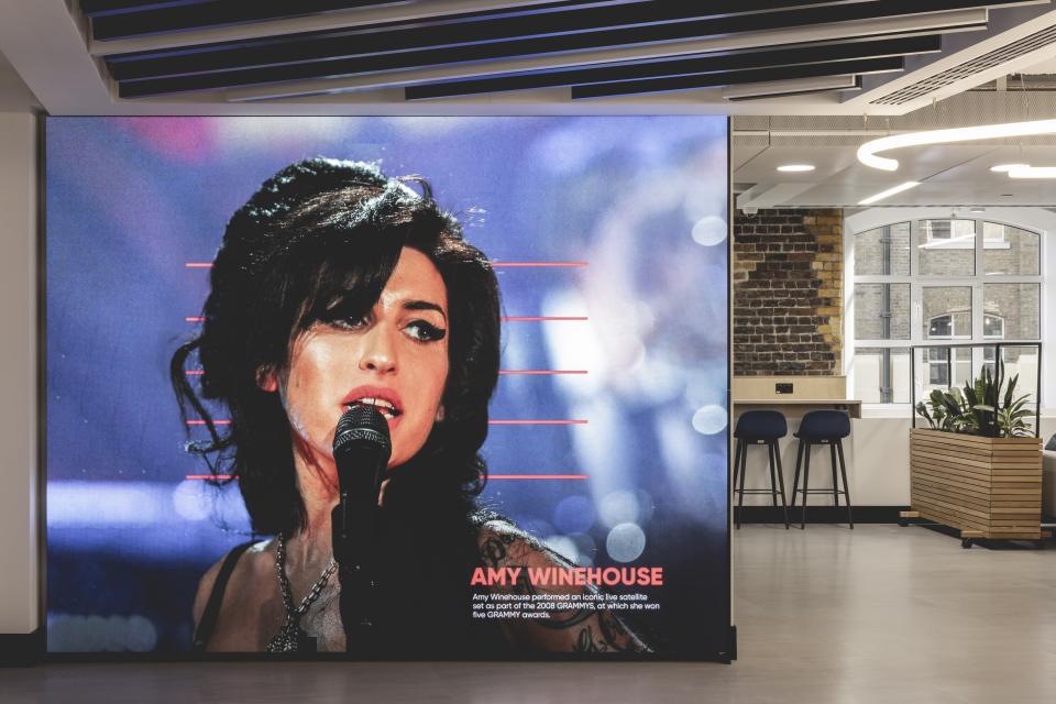 Large wall screen displaying a portrait of Amy Winehouse in a music-themed workspace designed by Ekho Studio.