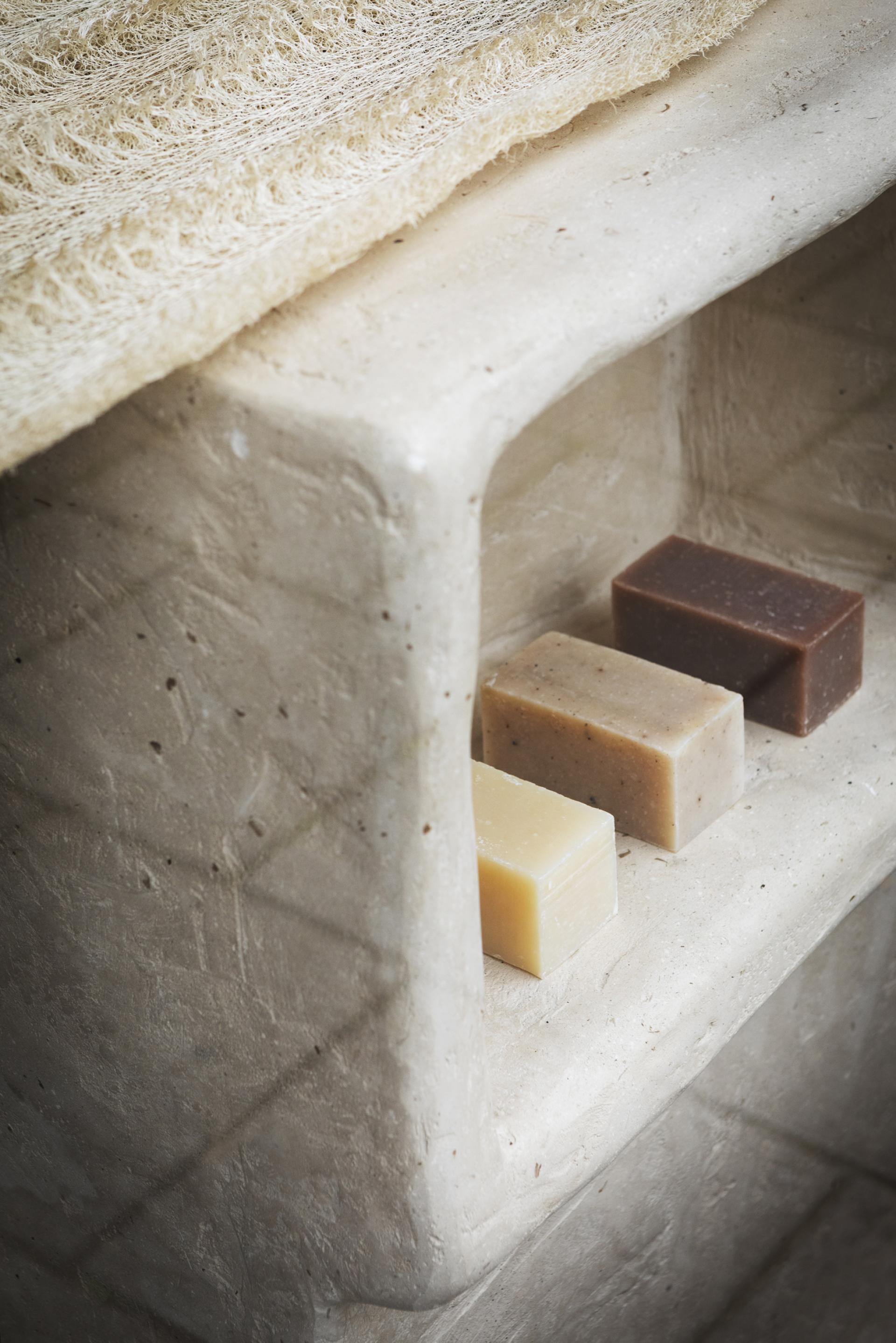Natural soaps displayed on a textured, eco-friendly stone shelf, showcasing sustainable materials in retail design.