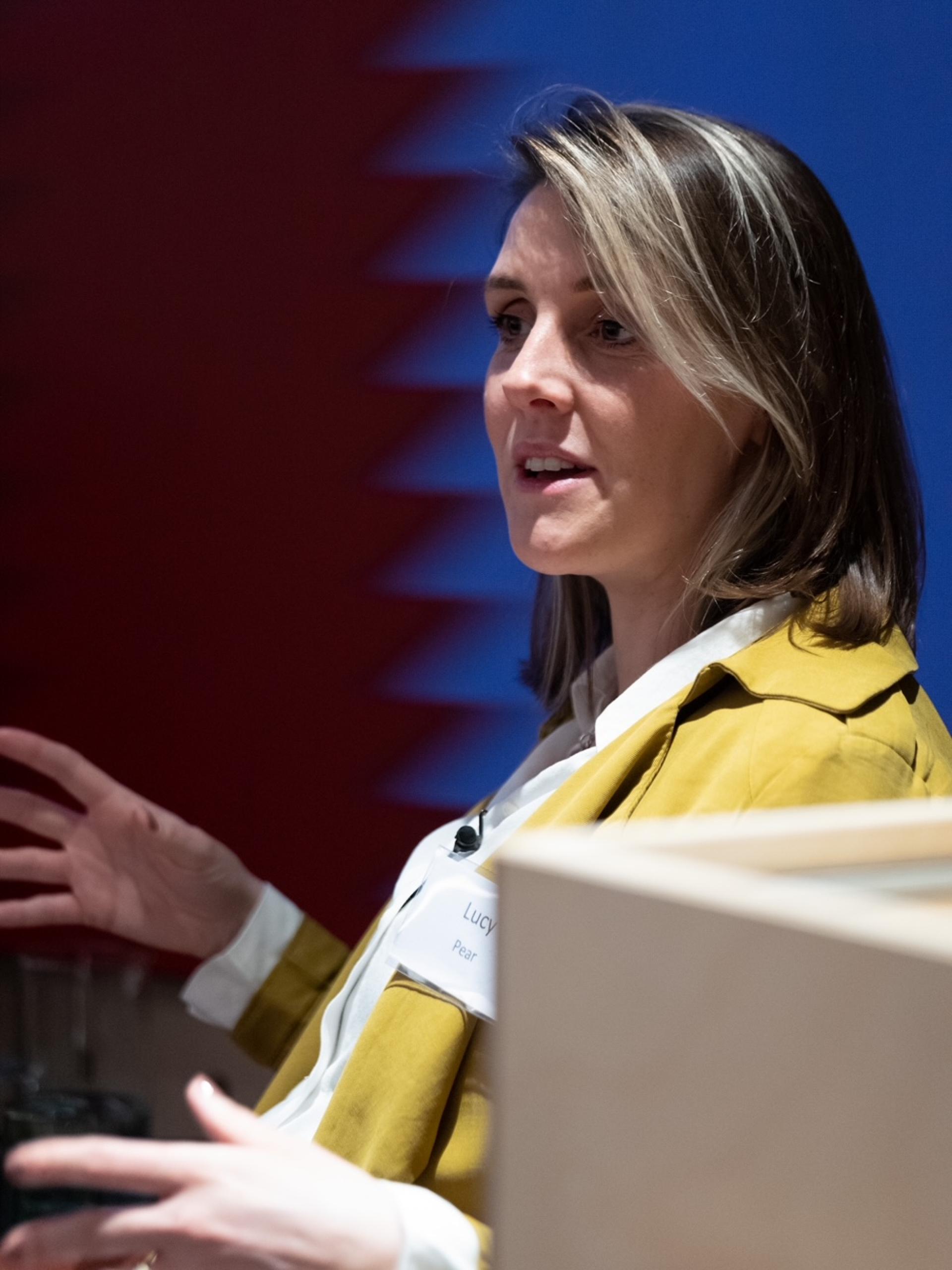 A speaker passionately discussing the intersection of brand and experience in hospitality during a seminar event.