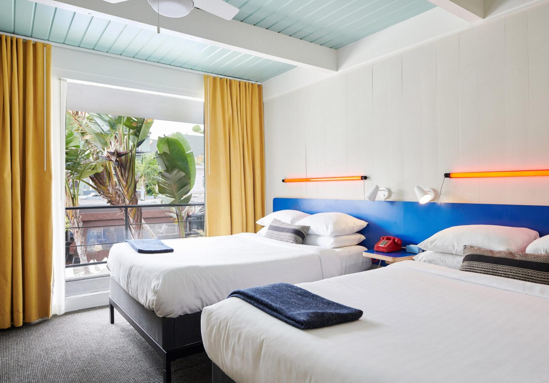 Brightly designed hotel room at the Phoenix Hotel, featuring twin beds, vibrant curtains, and tropical views in San Francisco.