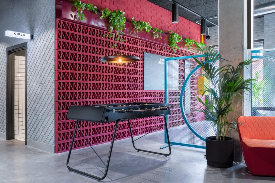 Modern co-living space at The Student Hotel in Barcelona featuring a foosball table, vibrant decor, and greenery.
