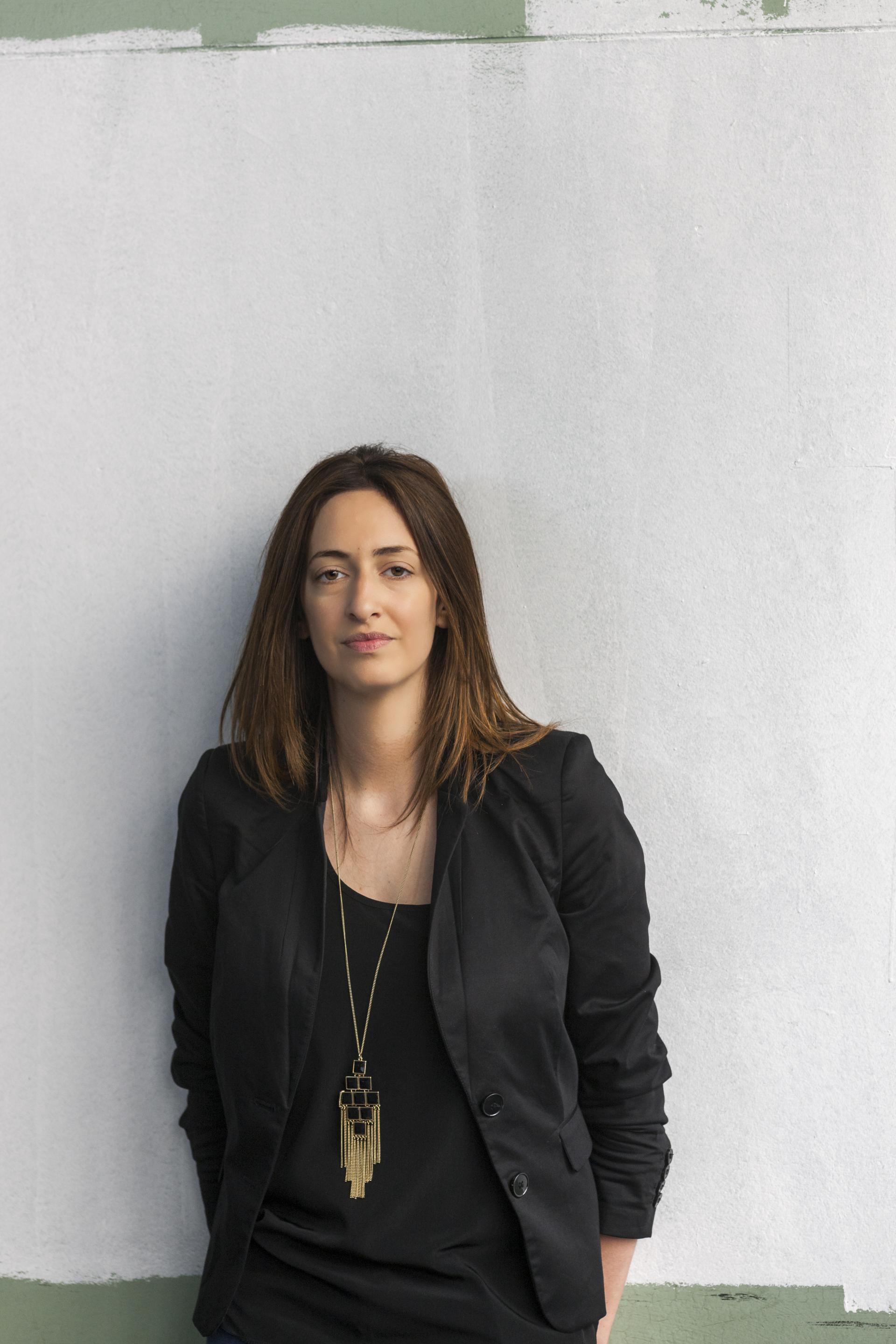 Contemporary designer posing against a textured wall, promoting discussions on sustainable design and nature connection.
