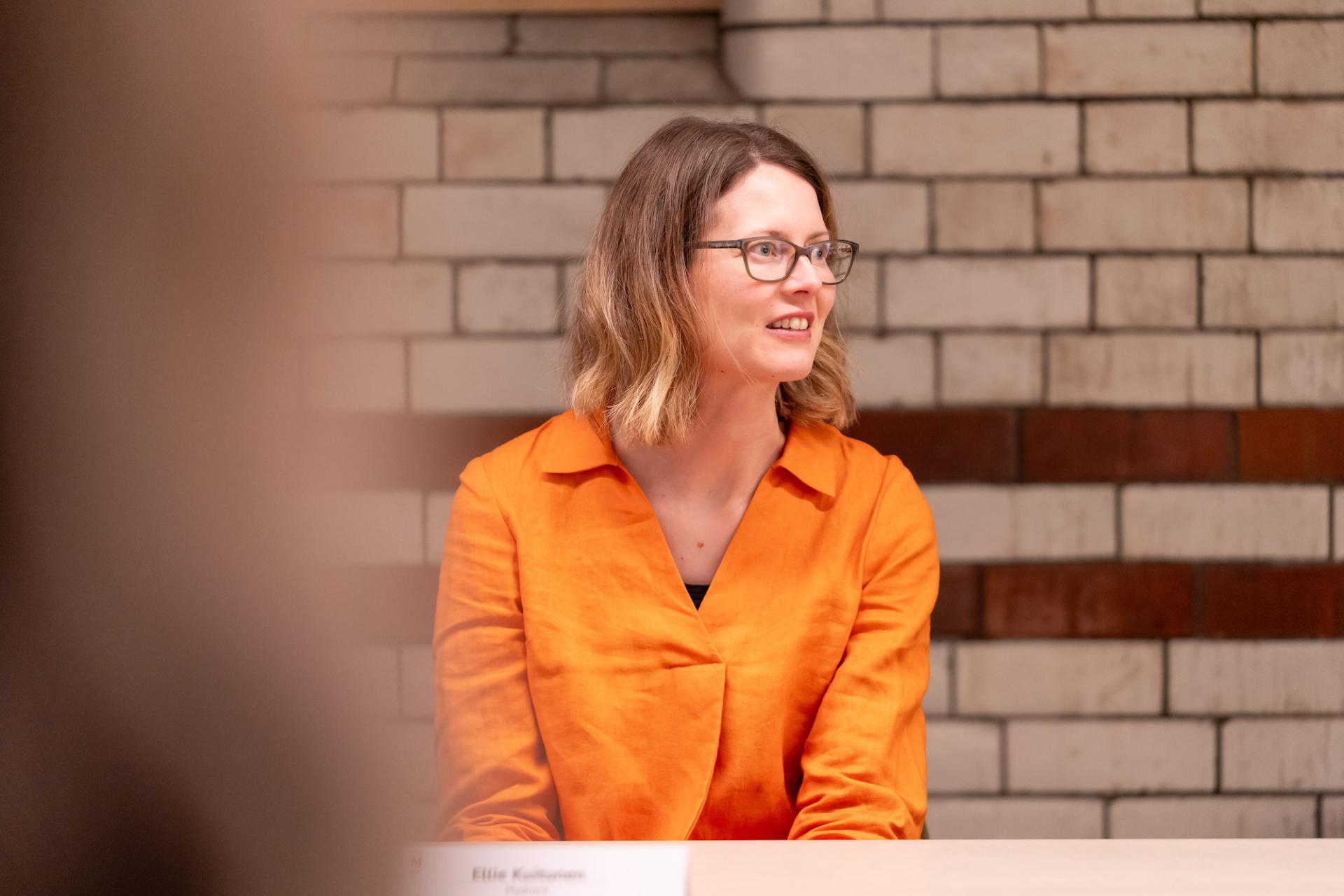 Woman in an orange shirt participates in a roundtable discussion about sustainability and value engineering.