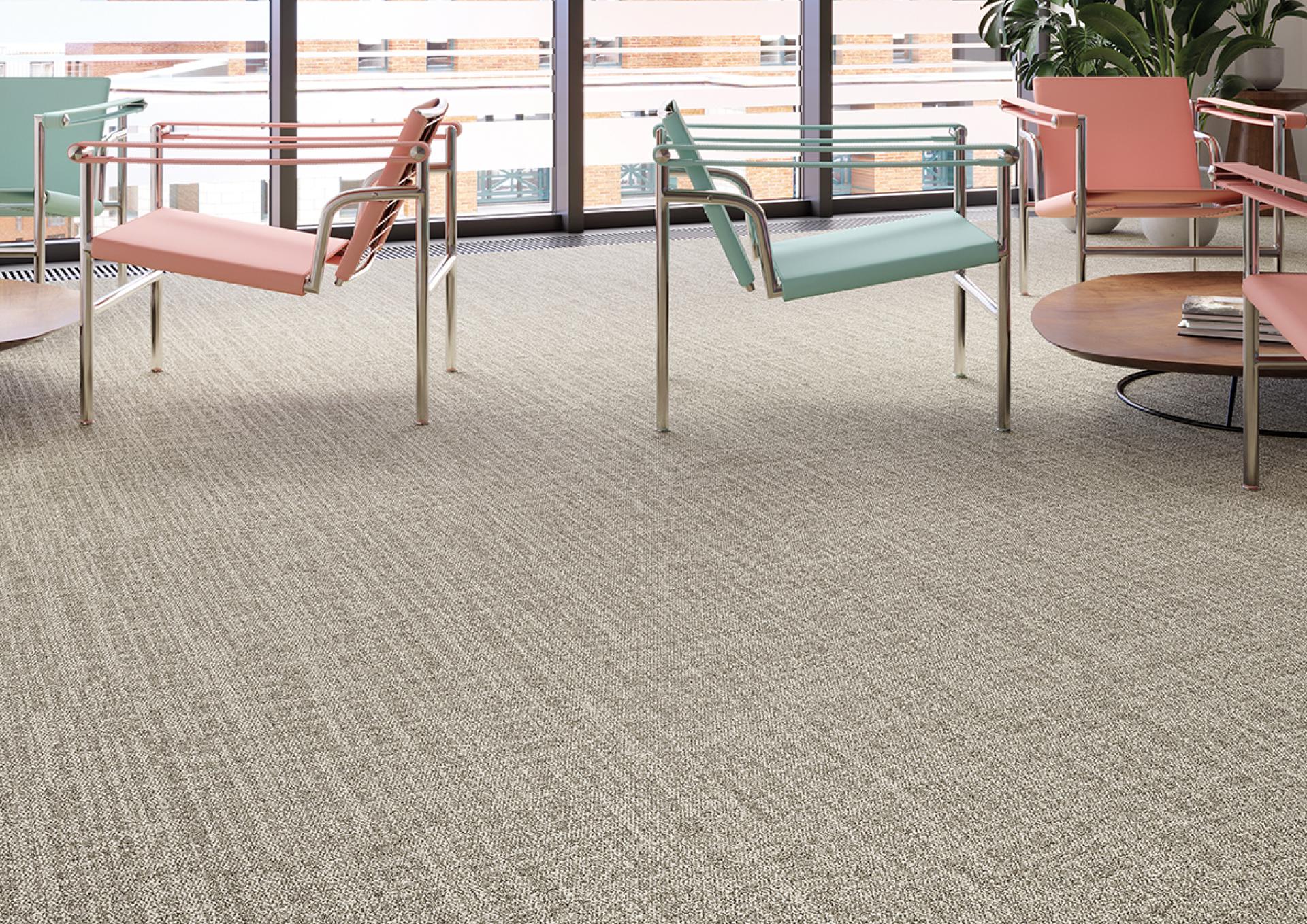 Tessera Accord flooring enhances modern office space with soft striated carpet design, featuring colorful contemporary chairs and a coffee table.