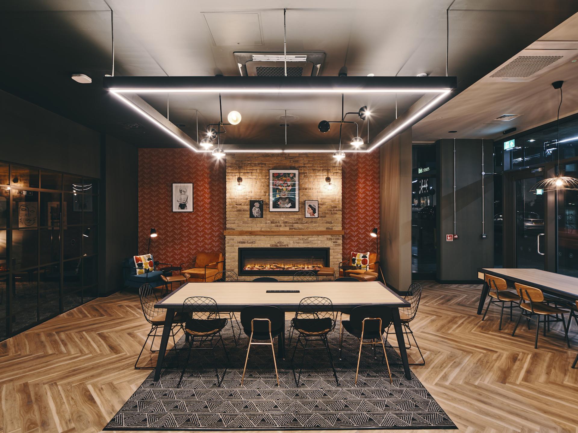 Sophisticated student amenity space showcasing modern furnishings, warm lighting, and a cozy fireplace designed by 74.