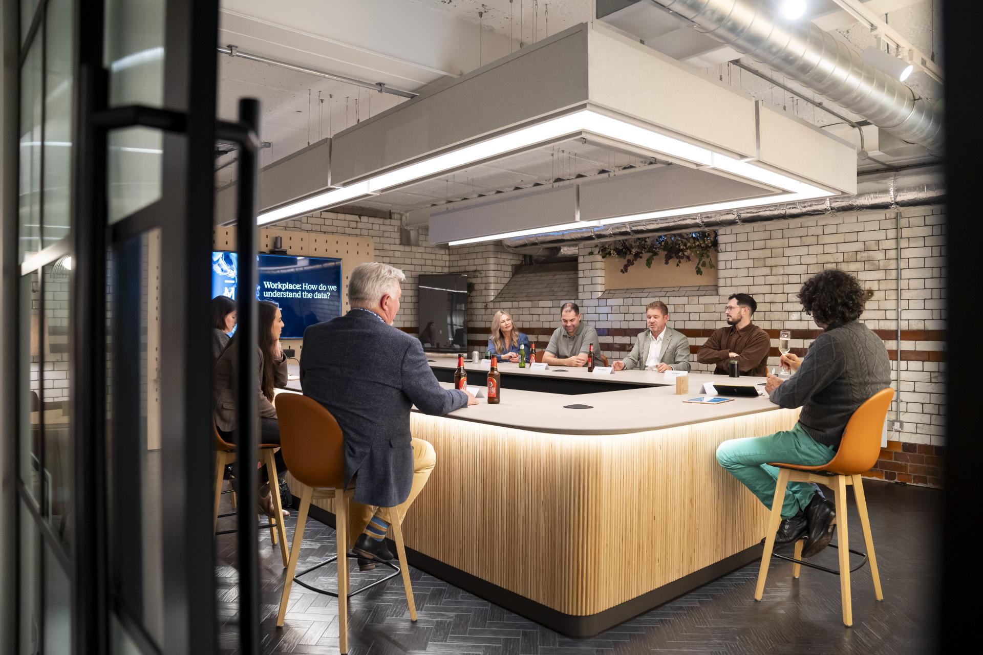 Collaborative meeting at a modern workspace, discussing data's impact on workplace dynamics and technology.