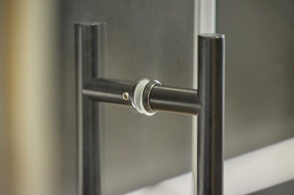 Elegant black metal door handle showcasing modern design in a stylish residential wine room by Glass + Mirror Technology.