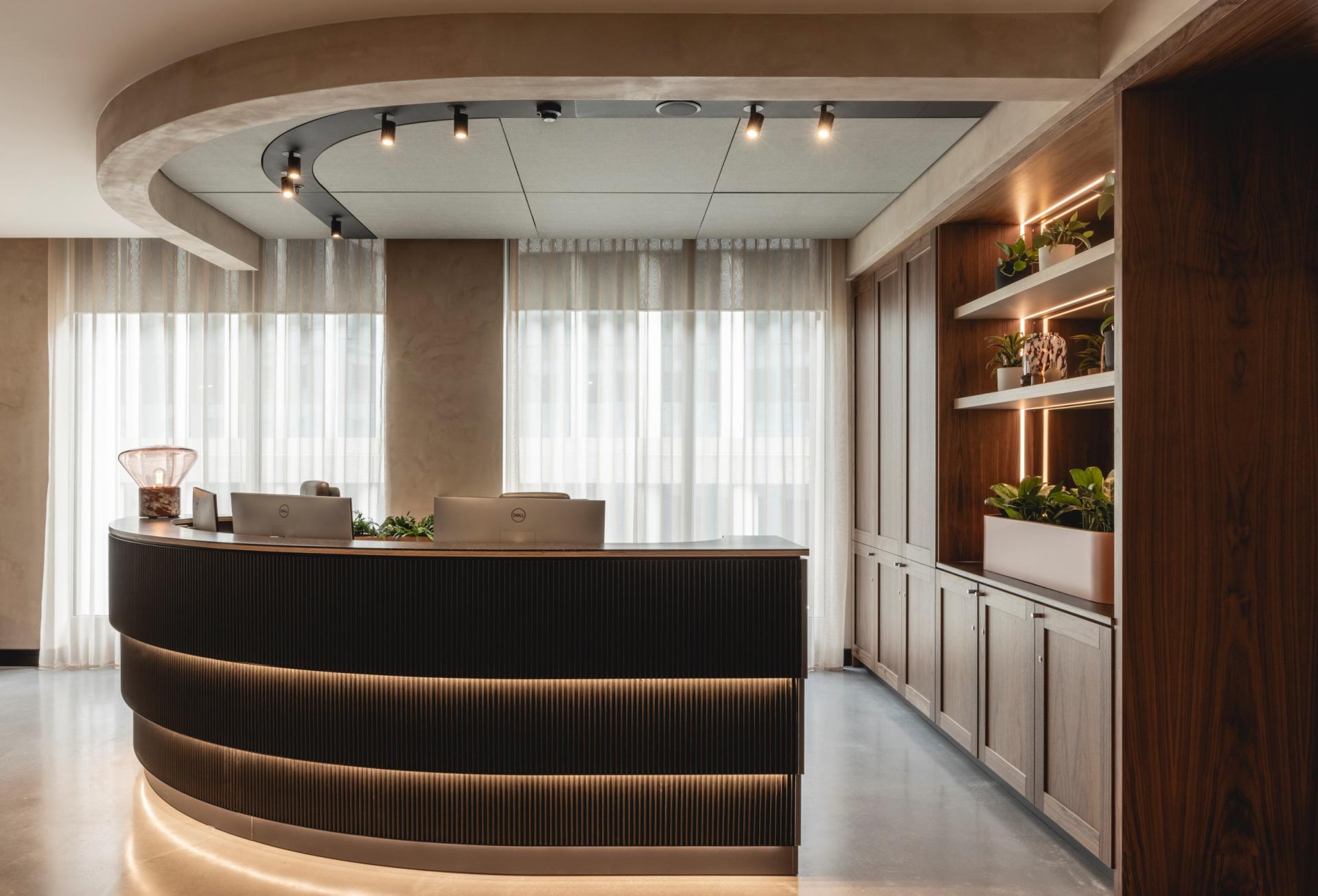 Stylish reception area featuring Art Deco curves, natural light, and greenery, designed for a calming workplace environment.