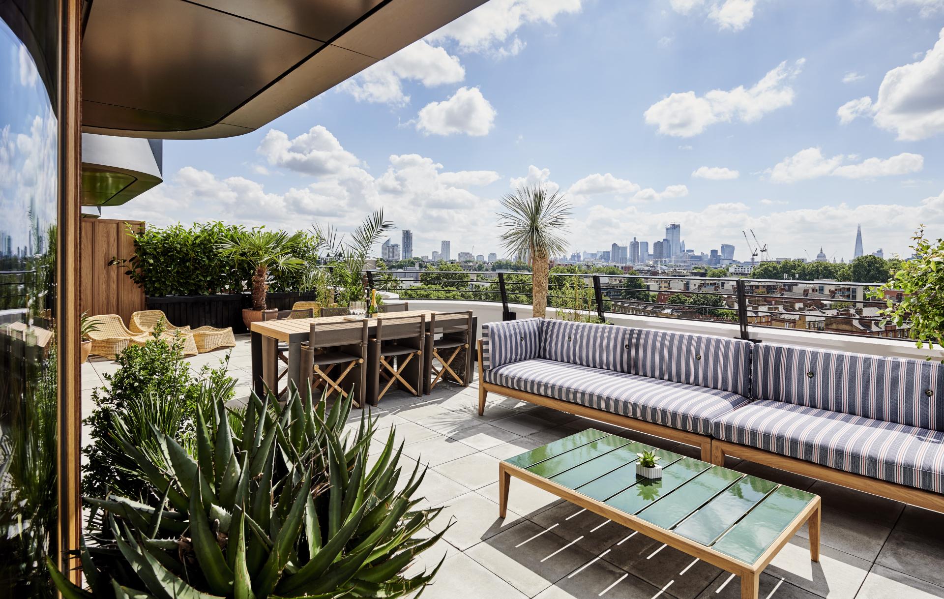 Rooftop terrace at The Standard, London, featuring stylish seating, greenery, and panoramic views of the city skyline.