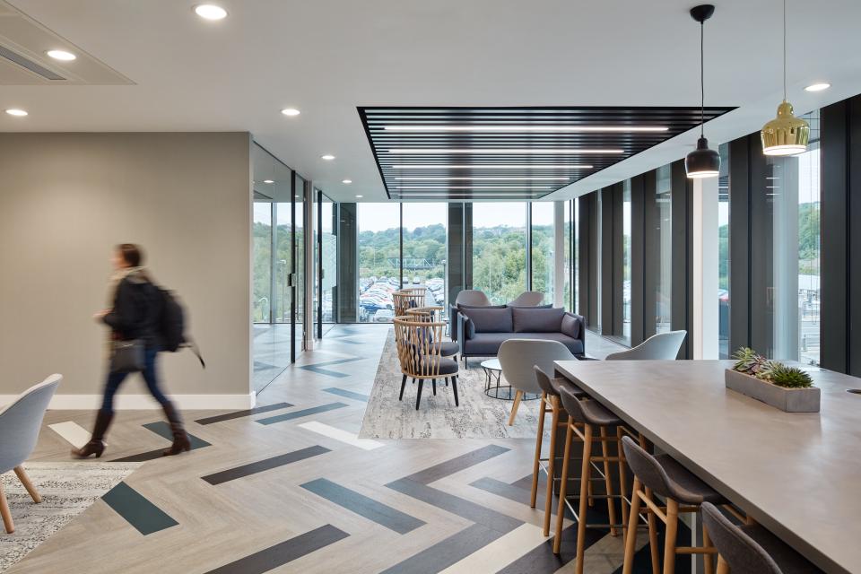 Modern office interior featuring open workspace, stylish seating, and large windows overlooking a green landscape, designed for healthcare professionals.
