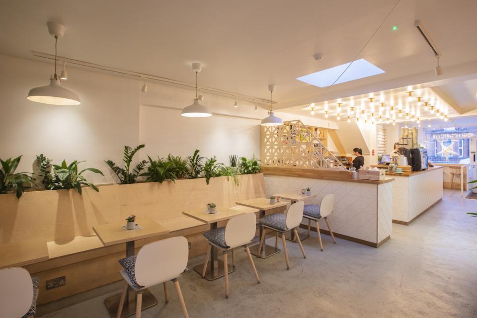 Modern café interior featuring wooden tables, potted plants, and an inviting service counter designed by Liqui Group in Dublin.