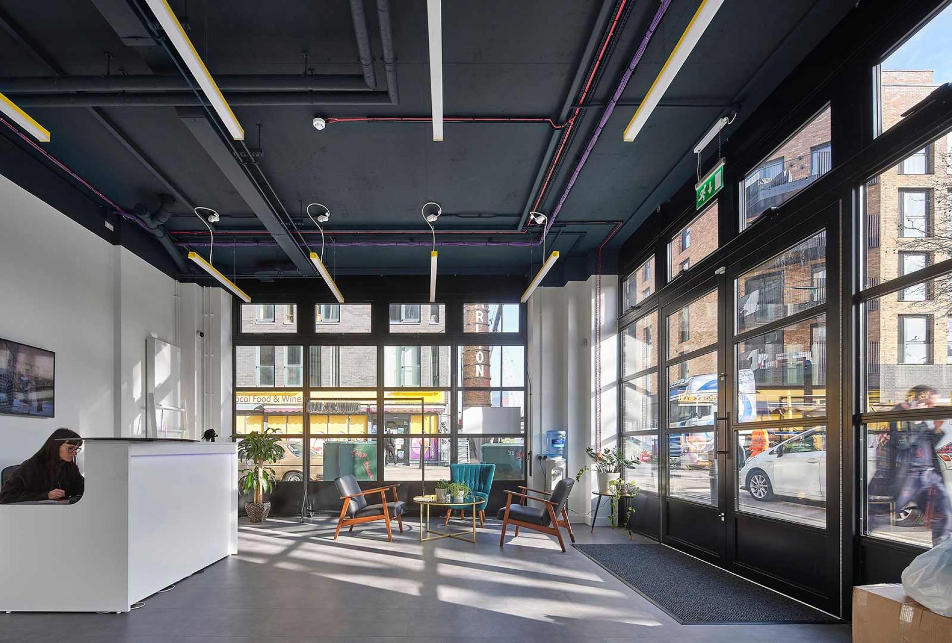 Contemporary workspace interior featuring a reception area, stylish seating, and large windows with natural light.