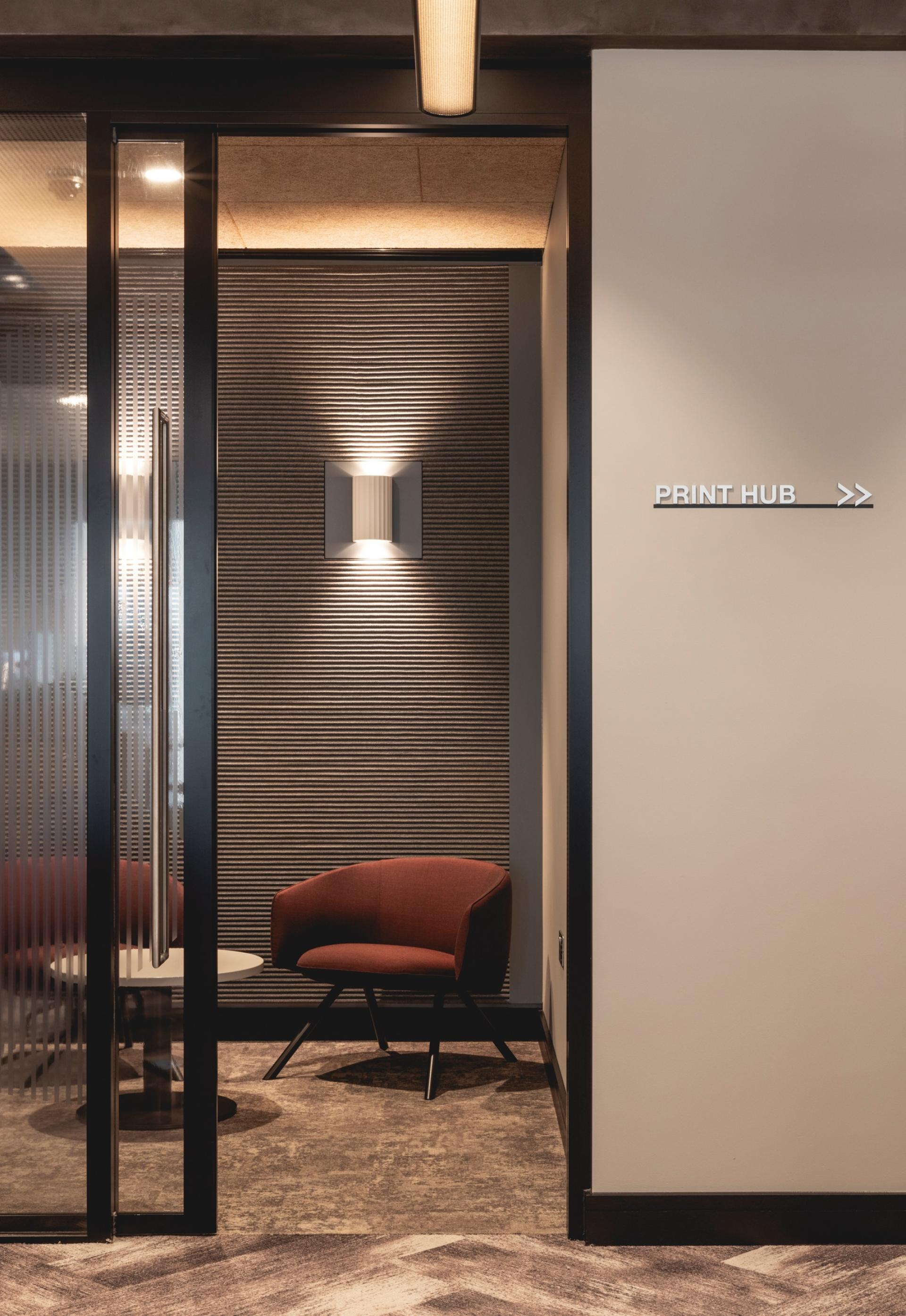 Modern workspace interior featuring Art Deco elements, a cozy chair, and a 'Print Hub' signage in calming colors.