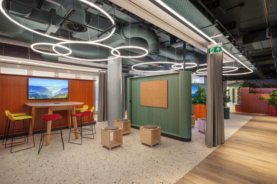 Modern office interior of PZ Cussons' Manchester headquarters with vibrant seating, circular lighting, and interactive design features.
