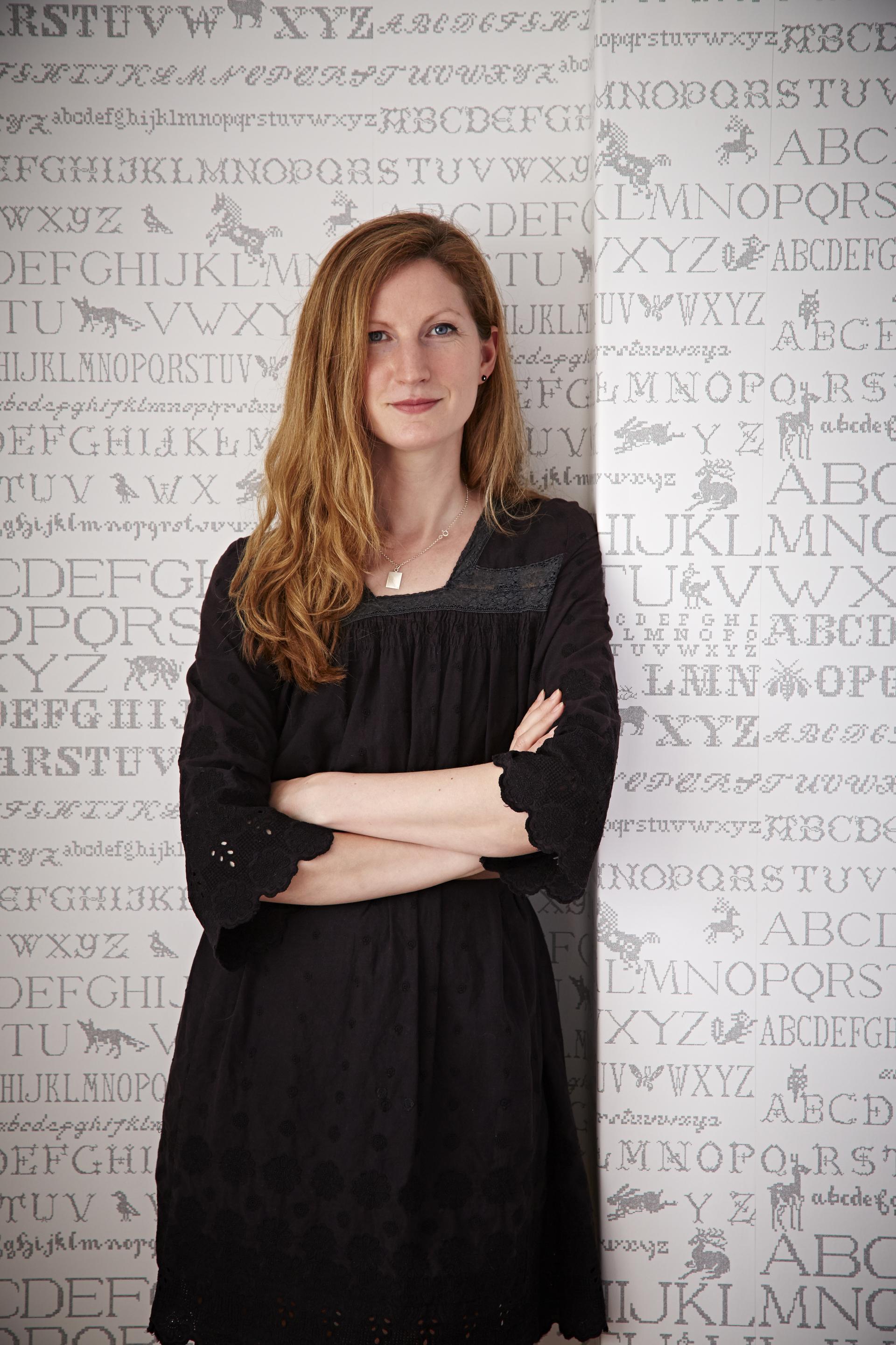 Designer Abigail Edwards posed confidently with her unique patterned wallpaper featuring whimsical letters and animals.