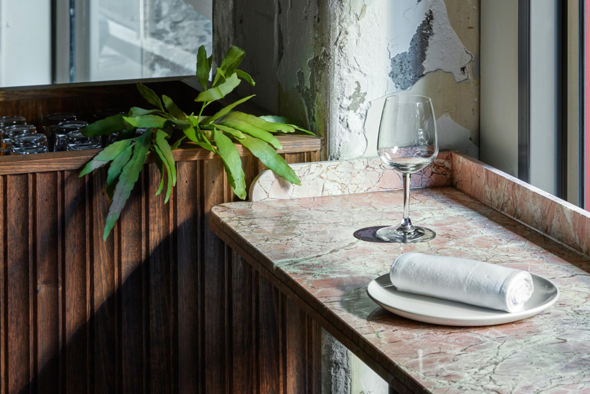Elegant marble countertop with a wine glass, plate, and green plant, reflecting the design of an Italian pasta bar.