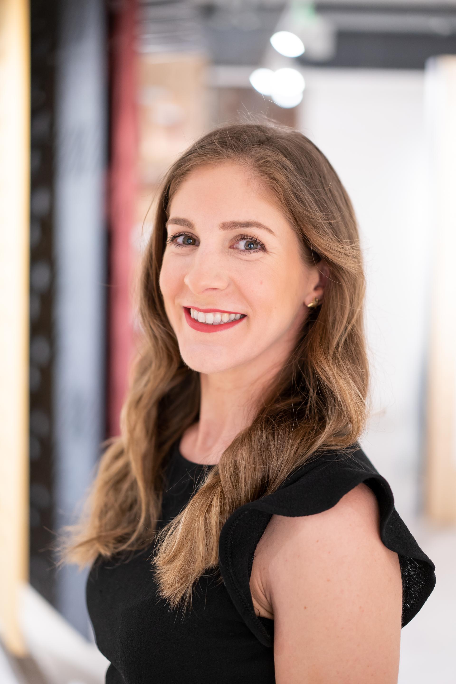 Professional woman smiling in a sustainable design space, reflecting themes of environmental responsibility and innovative solutions.