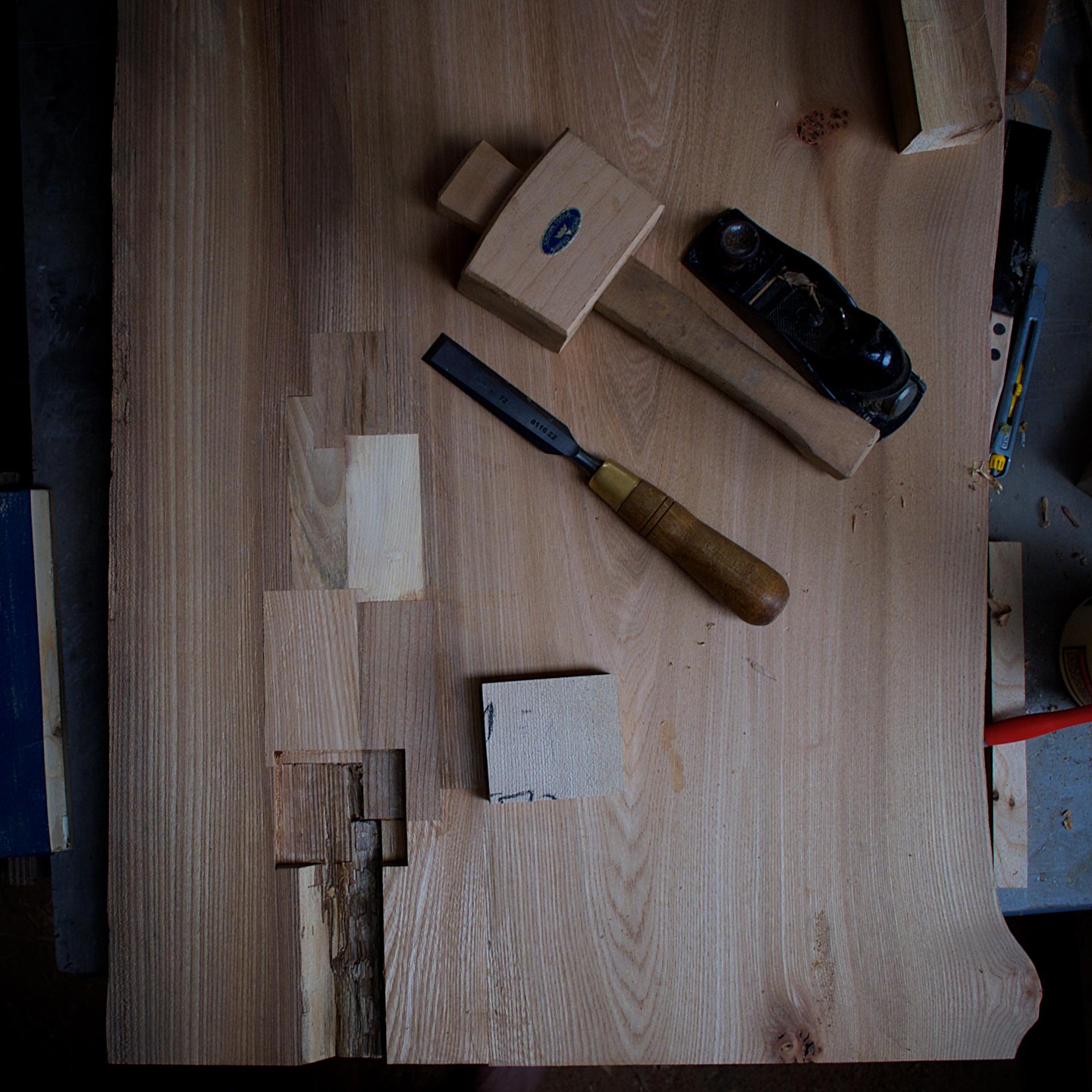 Woodworking tools including a chisel, mallet, and plane on a wooden workbench, illustrating sustainable furniture making processes.