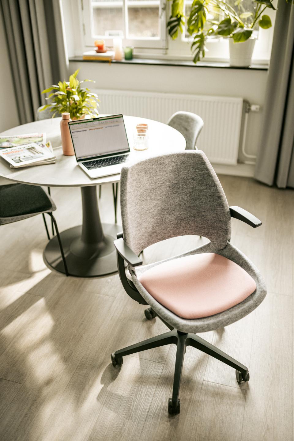 Be Hybrid task chair with recycled materials, positioned beside a stylish round table in a modern office setting.