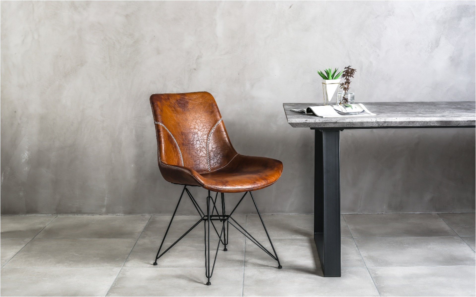 Stylish brown leather chair beside a modern concrete table, showcasing contemporary design trends at the Surface Design Show 2023.