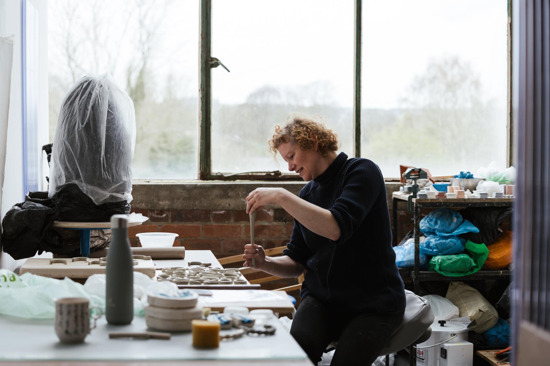 Ceramicist Jo Woffinden works in her studio, surrounded by clay tools and materials, showcasing the art of craftsmanship.