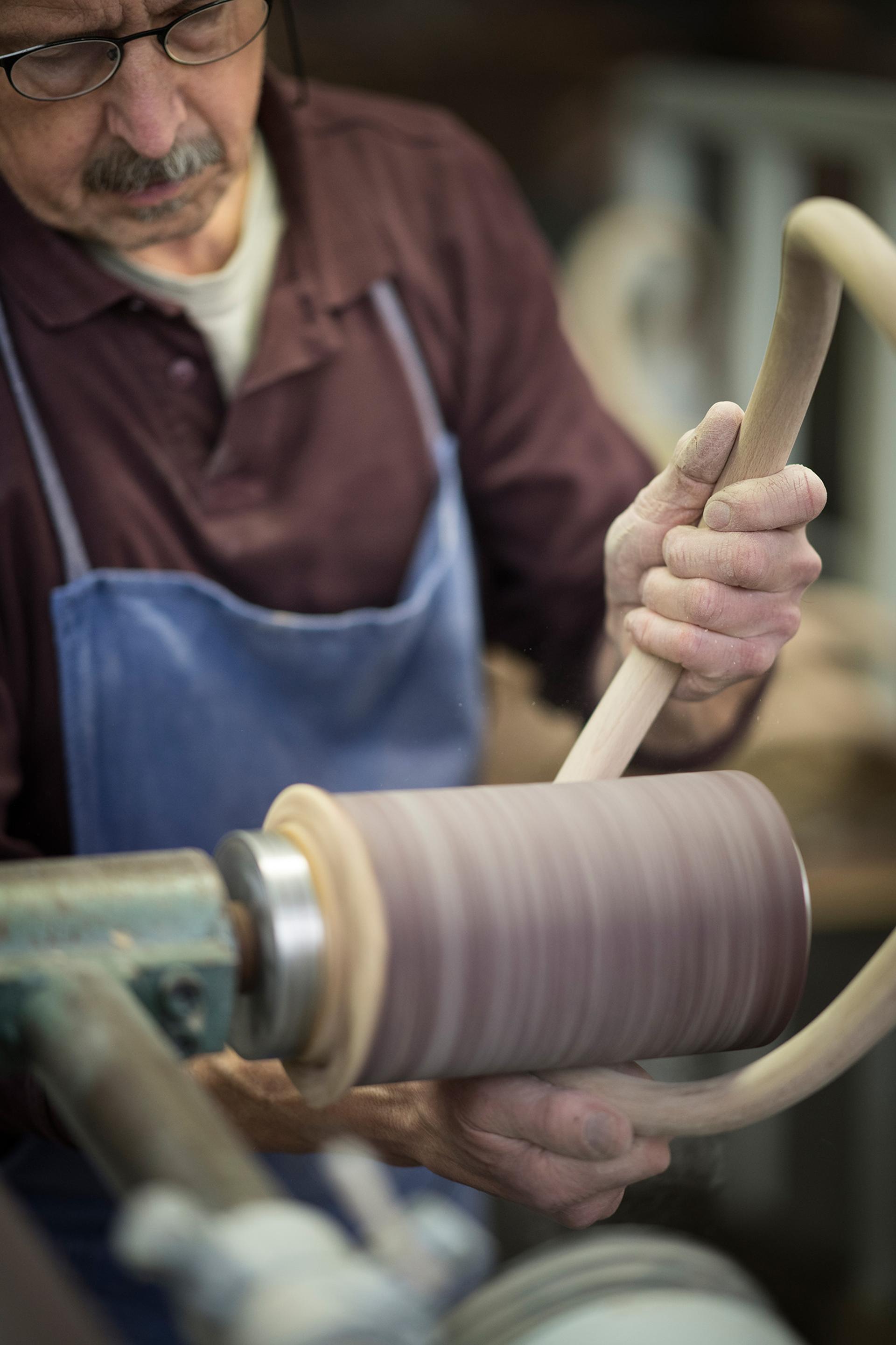 Craftsman shaping wood on a lathe, demonstrating Thonet's commitment to local production and craftsmanship in Germany.