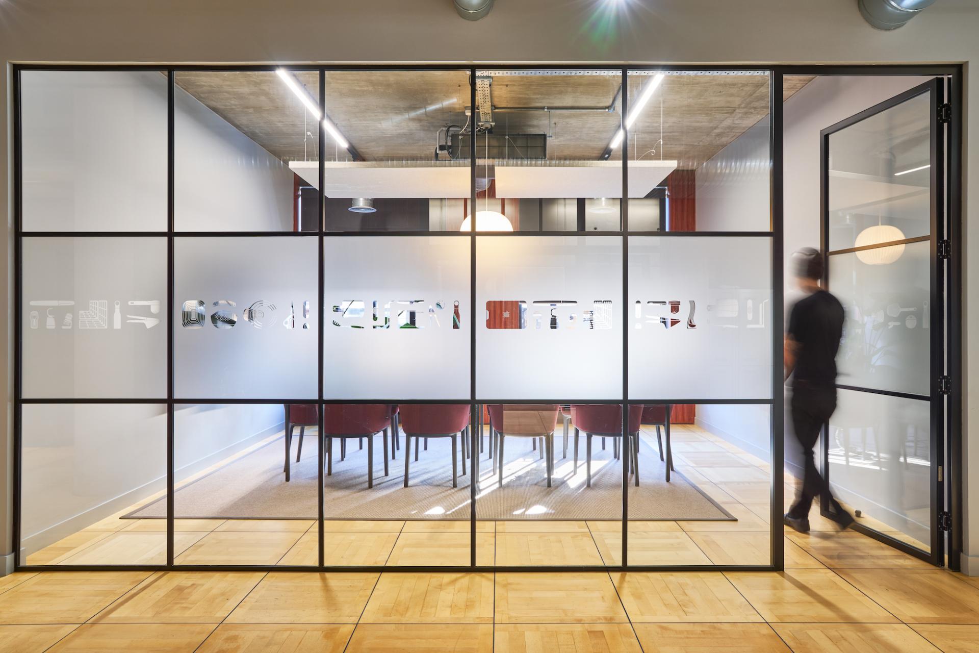 Modern London workspace with glass partitions, showcasing a design-focused meeting room for sustainable office refurbishment.