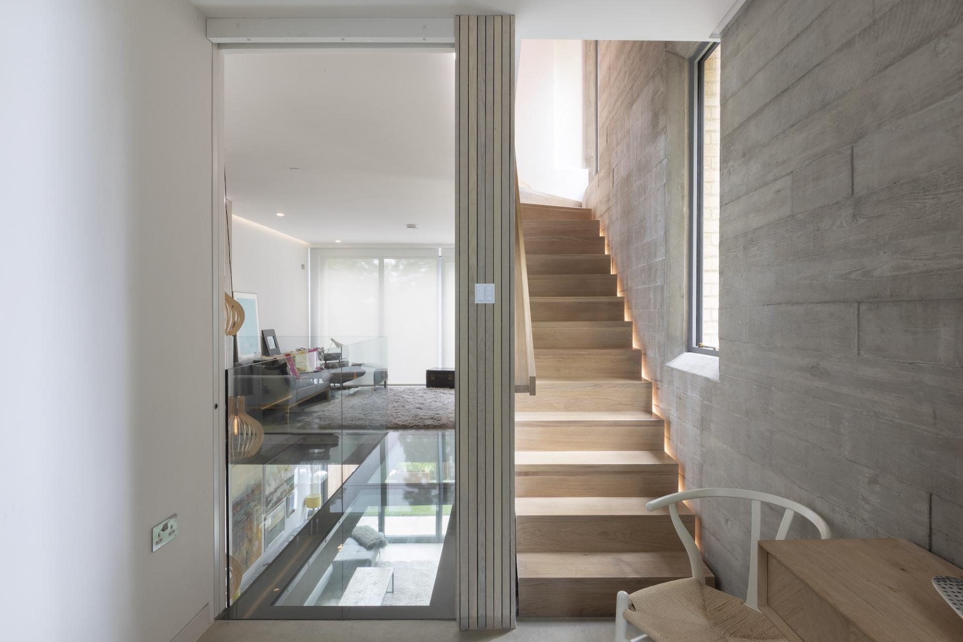 Modern interior showcasing a wooden staircase illuminated by natural light, highlighting the importance of design and lighting.