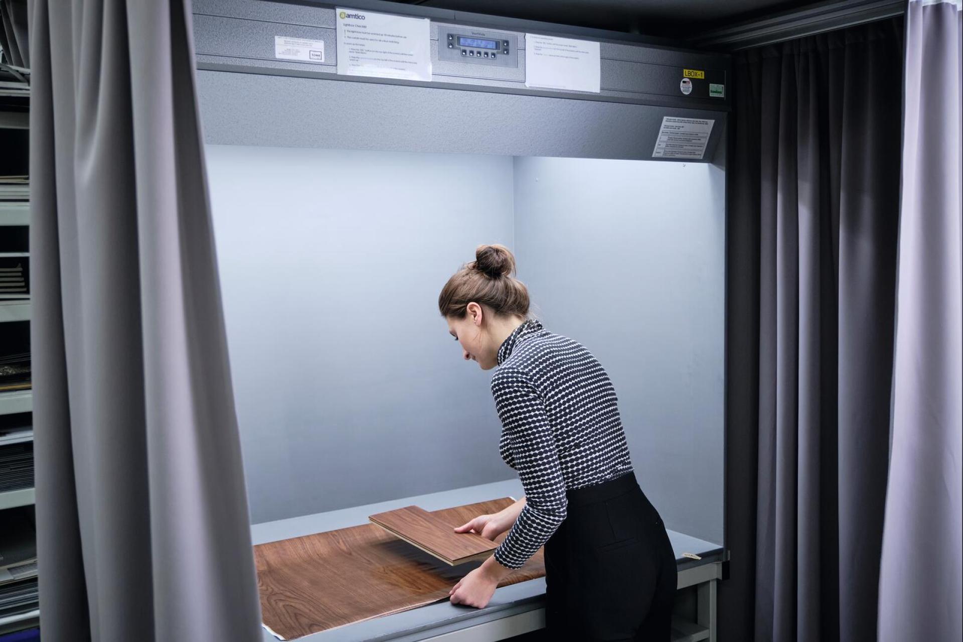 A person examines wooden flooring samples in a well-lit interior space, showcasing biophilic design elements.