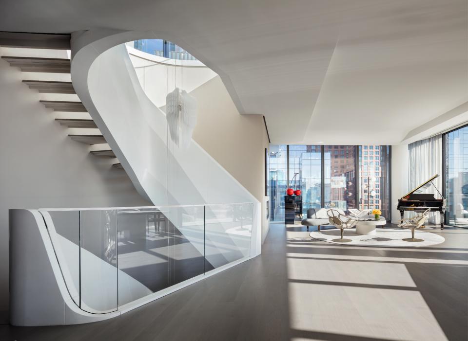 Luxurious interior of Zaha Hadid's West Chelsea penthouse featuring a sweeping staircase and elegant living area.