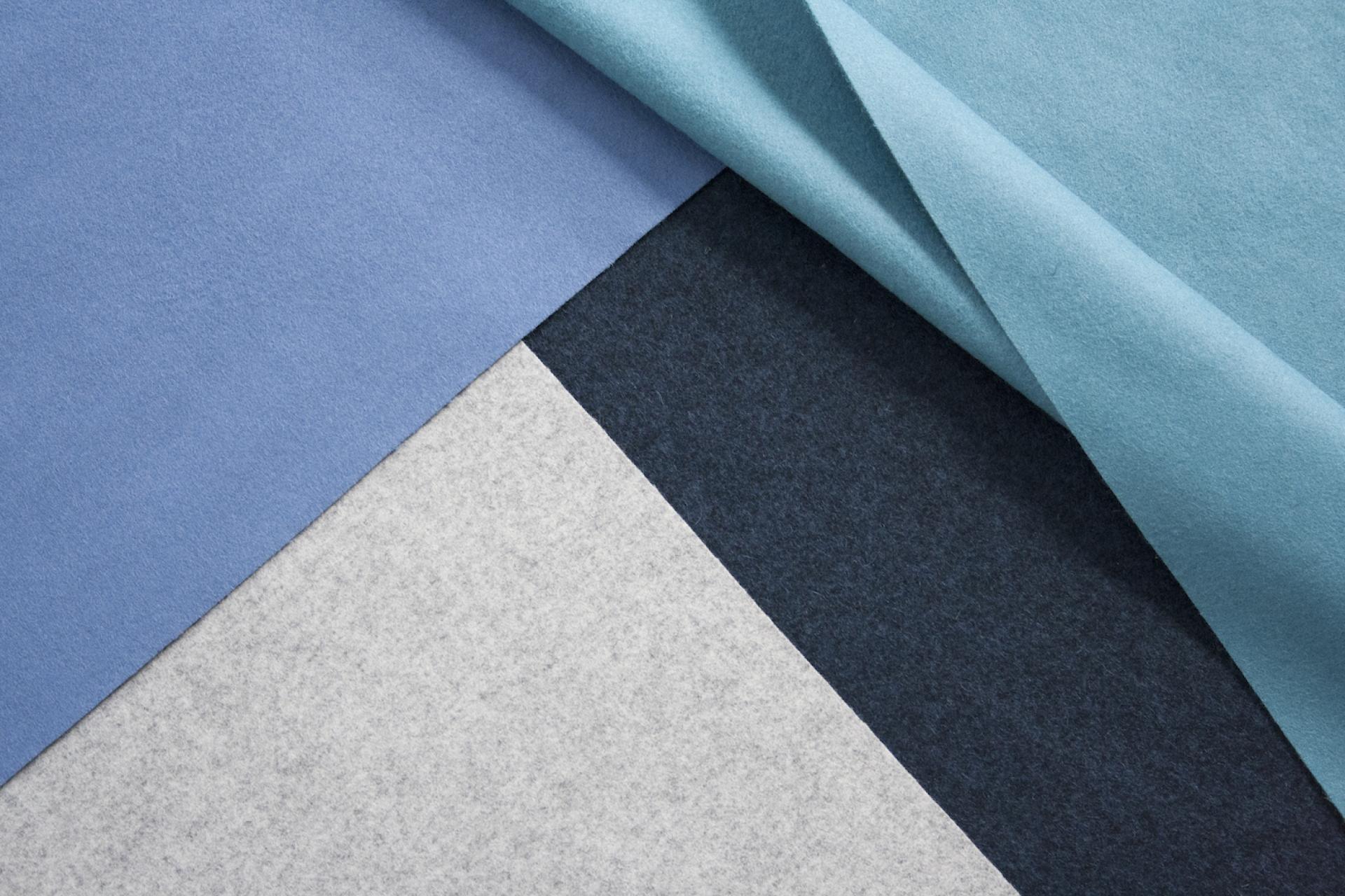 Various colored textile fabrics in shades of blue, gray, and black showcasing Camira's advanced textile treatment.