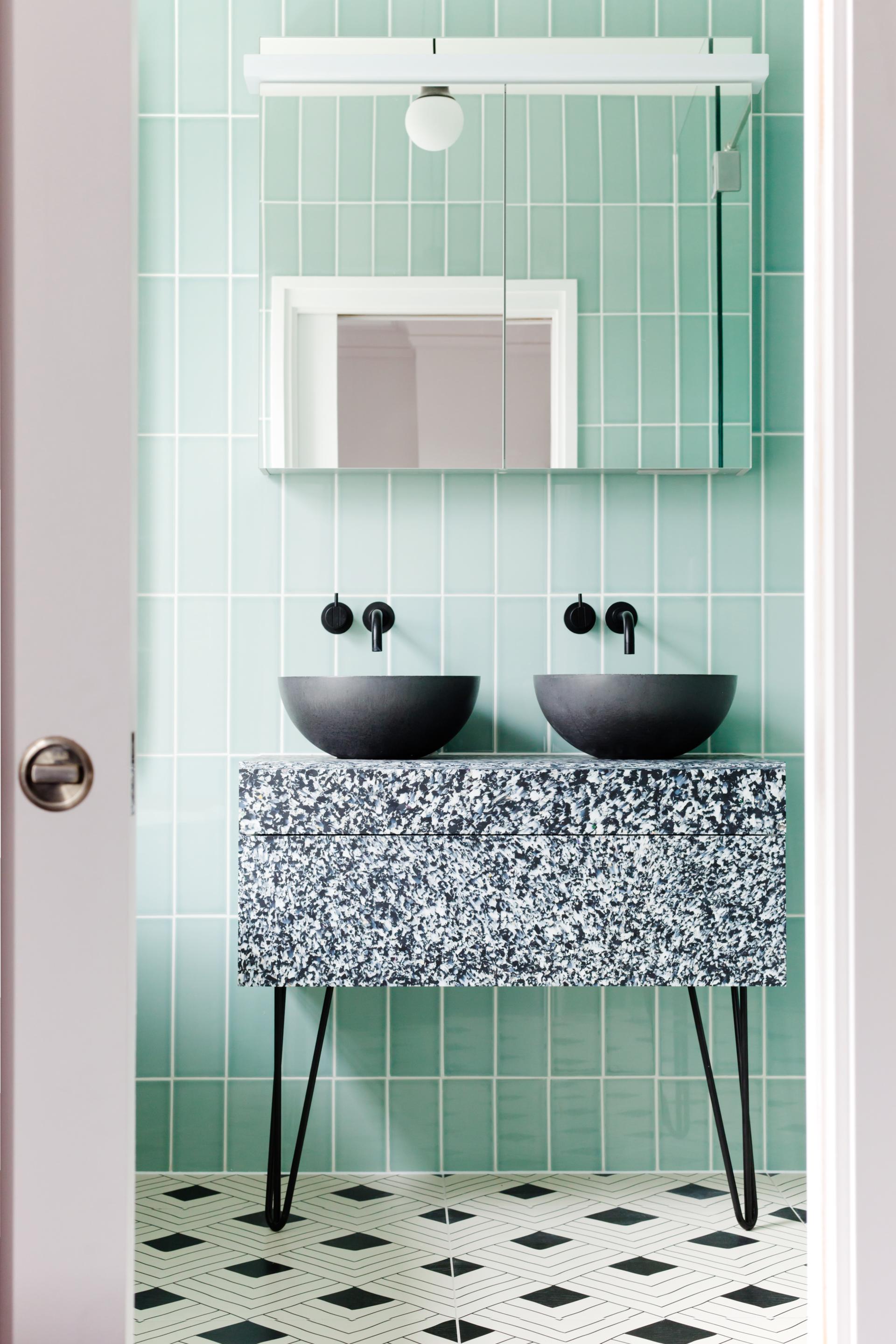 Sleek bathroom featuring handcrafted panels, black washbasins, and mint green tiles, showcasing sustainable design by Smile Plastics.