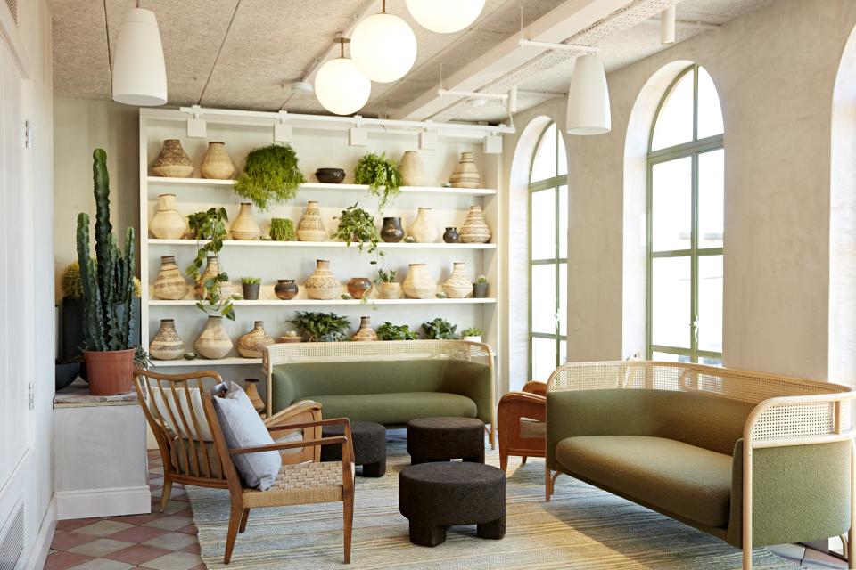 Stylish lounge featuring Scandinavian furniture and African crafts, with greenery and woven decor in a cozy setting.