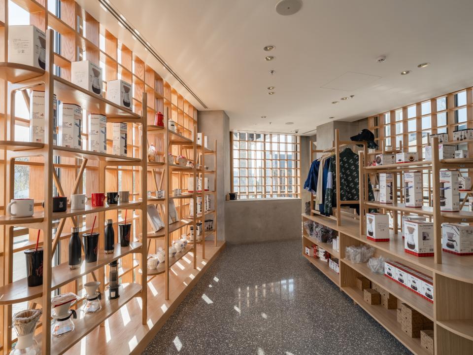 Brightly lit interior of a Brew92 coffee shop featuring wooden shelving displaying coffee products and decor in a Japandi style.